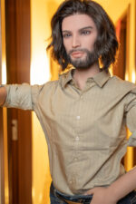 A mannequin with long dark hair and a beard wears a beige striped shirt and jeans, posed against a warmly lit background.