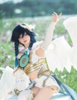 A cosplayer dressed as a winged character with blue hair and a white and gold outfit poses in a field of flowers.