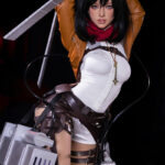 Cosplayer as Mikasa Ackerman holds vertical blade in white shirt, brown jacket, red scarf, and 3D gear against dark background.